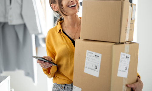 A woman holding a stack of two cardboard boxes